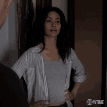 a woman is standing in front of a door with her hands on her hips and says excuse me .