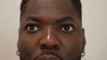 a close up of a man 's face with a beard looking at the camera with a serious look on his face .