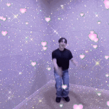 a man in a black shirt is dancing in a room surrounded by pink and green hearts