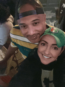 a man and a woman are posing for a picture and the woman is wearing a green hat