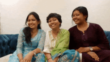 three women are sitting on a couch and smiling