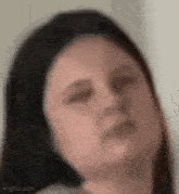 a close up of a woman 's face with her eyes closed and a blurred background .