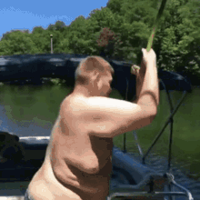 a shirtless man on a boat holding a fishing rod