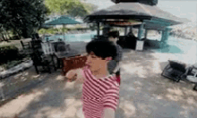 a man in a red and white striped shirt is dancing on a beach .