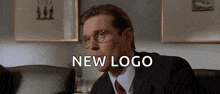 a man in a suit and tie is sitting in a chair with the words `` new logo '' written below him .