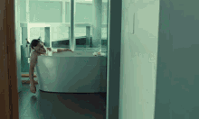 a man laying in a bathtub with a bottle of wine