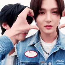 two boys are making a heart shape with their hands .