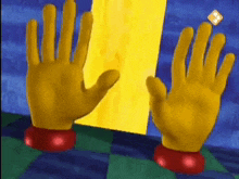 a pair of yellow gloves are standing next to each other in front of a yellow wall .