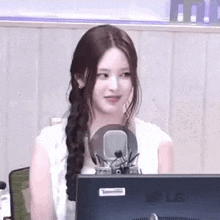 a woman is sitting in front of a microphone in front of an lg computer monitor .