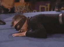 a man is laying on the ground in a wrestling ring with a mask on .