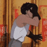a man in a tank top and gloves is covering his face with his hands .