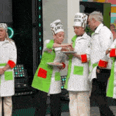 a group of people wearing chef hats and aprons are standing next to each other .