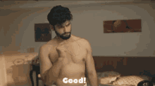 a shirtless man is standing in front of a bed with the word good written below him