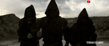 three people in hooded robes are standing in the desert with the words terbaik ke langit written on the bottom