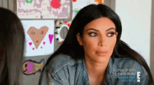 kim kardashian is sitting in front of a wall with drawings on it .