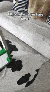 a couch with a cow print rug and the words oh how the tables have turned