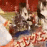 a blurry picture of a person sitting at a table with a bottle of soda on it .