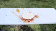 a white table with a hamburger and a bun on it