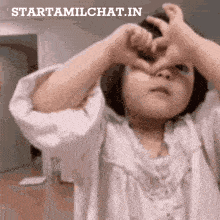 a little girl making a heart shape with her hands with the words starttamilchat.in below her