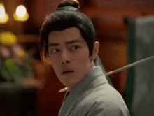 a man in a kimono is holding a sword in his hand and making a funny face .