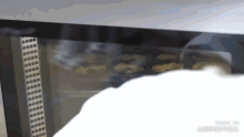a close up of a person taking a cookie out of a microwave oven
