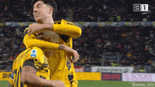two soccer players are hugging each other on a field with a dazn logo in the background