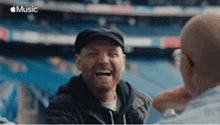 a man is laughing with another man in a stadium .