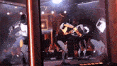 a group of robots are dancing in a room with a sign that says ' clock ' on it
