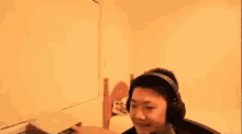 a man wearing headphones is sitting in a room with a laptop .