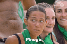 a group of women wearing green scarves are standing next to each other and one of them is wearing braces .