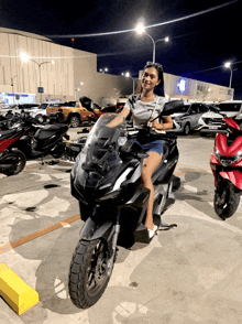 a woman sitting on a motorcycle in a parking lot