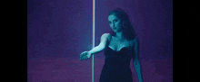 a woman in a black dress is holding a blue light in her hand .