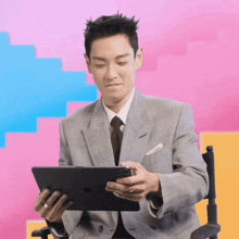 a man in a suit is sitting in a chair holding a tablet