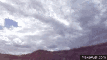a gif of a cloudy sky with mountains in the background