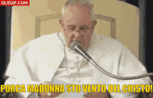 a man speaking into a microphone with the words porca madonna sto vento del cristo written below him