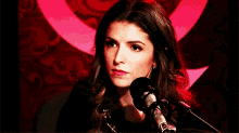 a woman stands in front of a microphone and smiles