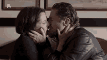 a man and a woman are kissing in front of a sign that has the letter a on it