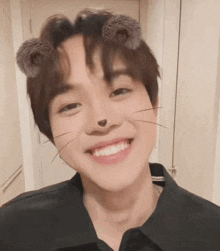 a young man with a cat mask on his face smiles