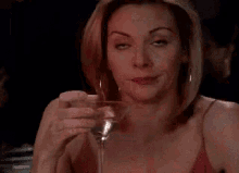 a woman is drinking a martini in a glass at a table .