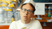 a man wearing glasses and a chef hat is looking at the camera
