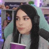a woman wearing headphones is drinking from a purple cup