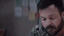 a man with a beard is sitting at a table in a room .