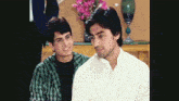 two young men are sitting next to each other and one is wearing a white shirt