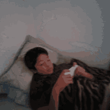 a young boy is laying on a bed playing a game