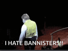 a man in a yellow vest stands on a stage with the words " i hate bannisters " written below him