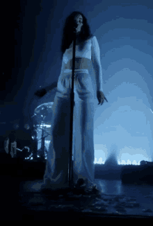 a woman is singing into a microphone in a dark room