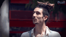 a man with a bun on his head is standing in front of a sign that says talent on it