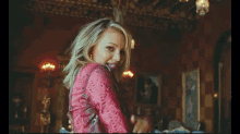 a blonde woman in a red dress is dancing in a room