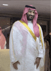 a man in a white robe and a red and white checkered head scarf smiles
