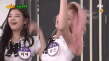two girls are standing next to each other with their arms in the air .